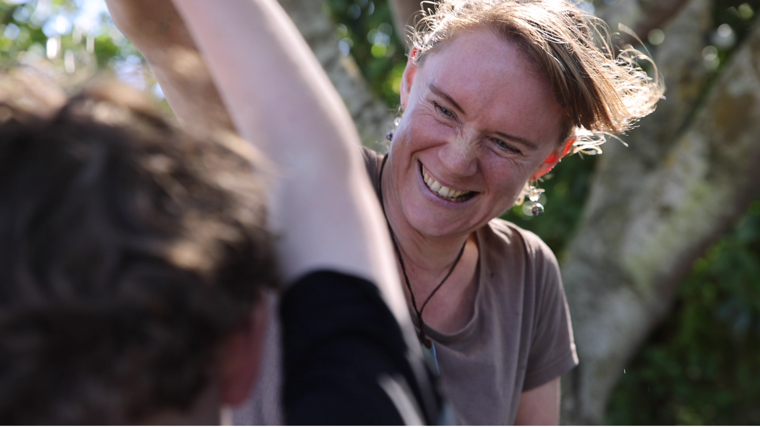 A woman smiling and having a water fight with her son whose back is to the camera.