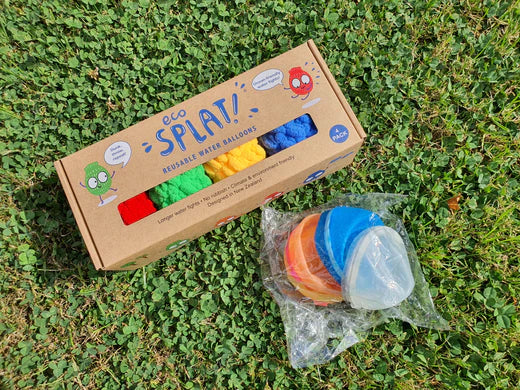 A box of EcoSplat reusable water balloon and a packet of magnetic water balloons lying on the grass