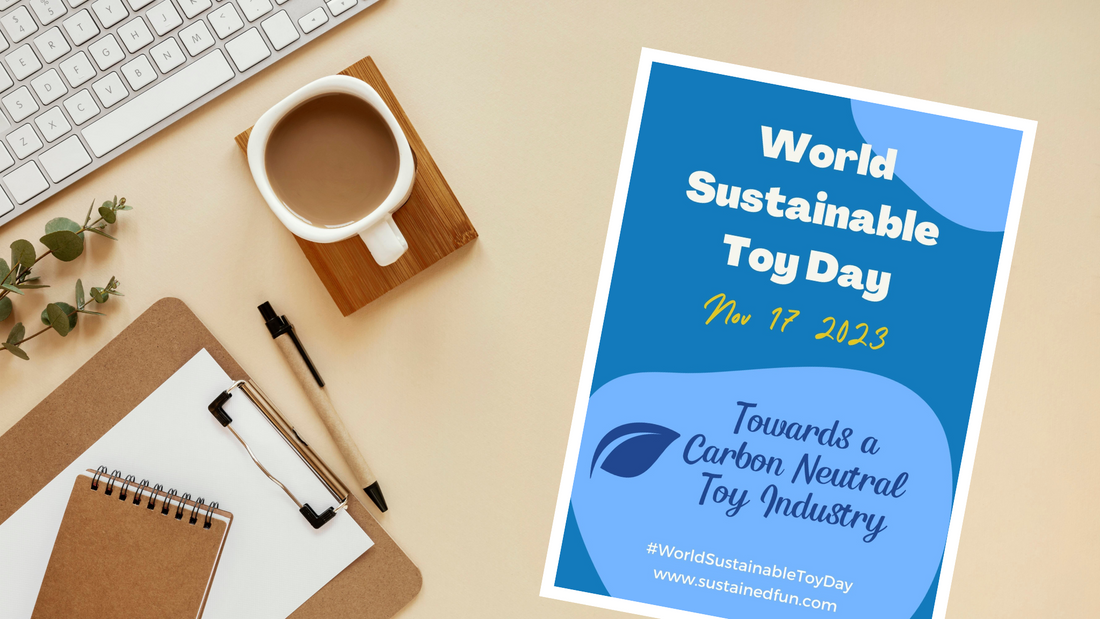 A stock photo looking down on a desk with a cup of coffee, a keyboard and a clipboard, with a poster advertising World Sustainable Toy day Nov 17 2023. Towards a Carbon Neutral Toy Industry