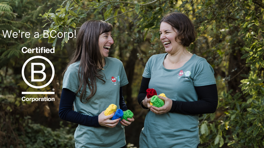 Anthea Madill and Helen Townsend standing in a garden, smiling at each other and holding EcoSplat Reusable water balloons. Red balloon. Text says Certified B Corp