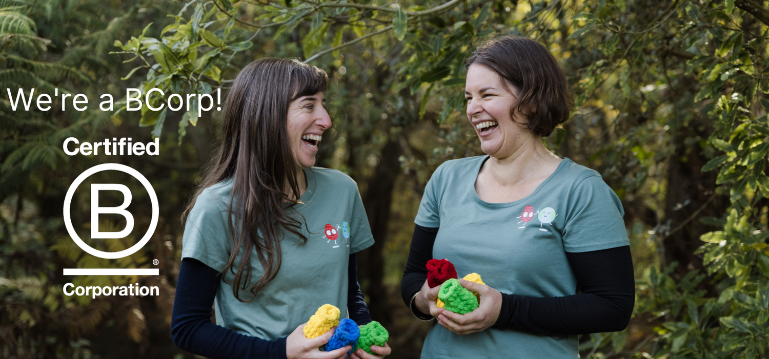 Anthea Madill and Helen Townsend in a garden, holding EcoSplat Reusable Water Balloons, looking at each other and laughing. Text on the photo says We're a B Corp! Certified B Corporation.